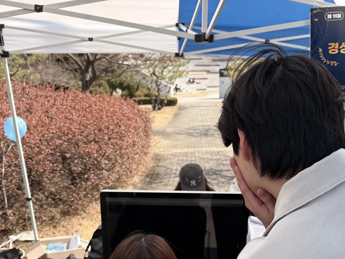 屋外のサークル博覧会ブースでAJOU ARCADEを体験する来場者